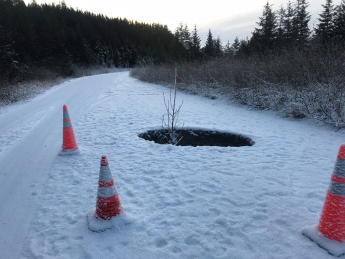 At Mile 19.5 traffic cones surrounds a large hole caused by a collapsed culvert. Perhaps a Christmas tree with a red light atop, rather than alder, should have been stuck in the ho-ho-hole. Photo by Dick Shellhorn/The Cordova Times