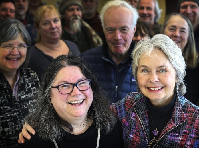 Mimi Briggs, left, and Michelle Hahn O’Leary pose for a portrait with friends and coworkers gathered behind them during the luncheon at the Cordova Legislative Information Offfice on Monday, Jan. 29, 2018. The luncheon honored the two for their decades of service to the LIO. Photo by Emily Mesner/The Cordova Times