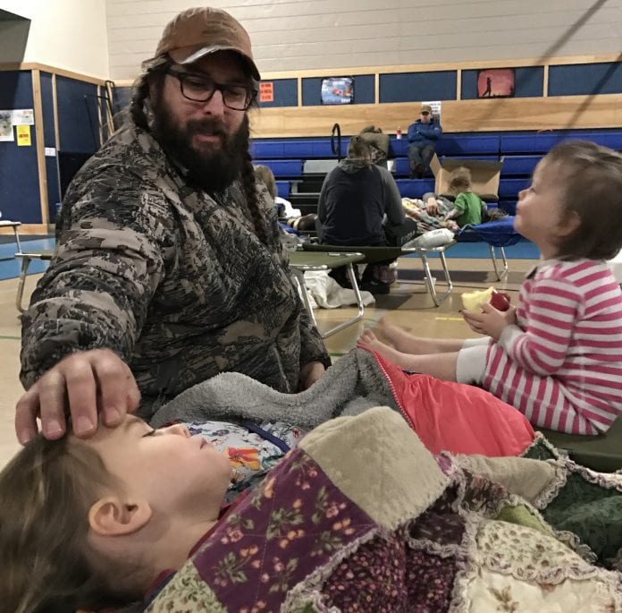 Heath Kocan sits with his daughters, Cora Kocan, 3, and Runa Kocan, 1, in the Mt. Eccles Elementary School gym at 2:24 a.m. while they take shelter during the tsunami warning on Tuesday, Jan. 23, 2018. Photo by Shelly Kocan/for The Cordova Times