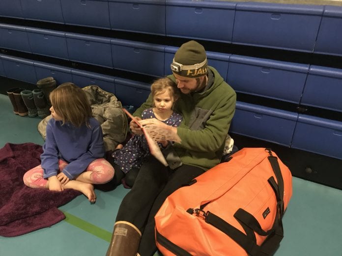 Kevin and Nora Haisman read to pass the time at the shelter, as Isla looks on. Check out their orange ‘To Go’ kit. Photo courtesy of Joanie Behrends