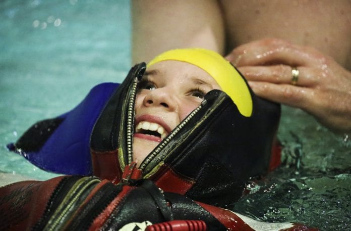 Third-grader Skyla Hallquist tests out a survival suit as Mt. Eccles physical education teacher Jeff Hamberger assists, at the Bob Korn Memorial Pool on Friday, Feb. 2, 2018. Photo by Emily Mesner/The Cordova Times