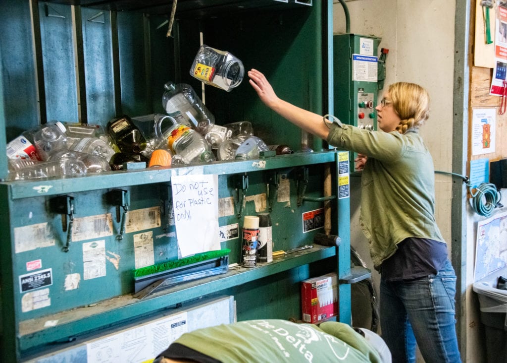 Copper River Watershed Project Operations Manager Shae Bowman loads plastic bottles into a baler. (Aug. 7, 2019) Photo by Zachary Snowdon Smith/The Cordova Times