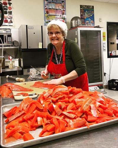 Sandy Whitmire prepares salmon for students at Mt. Eccles Elementary School on Thursday, Dec. 12. Photo by Alexis Osborn/for The Cordova Times